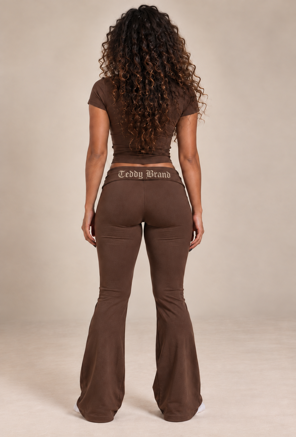 Back view of a model wearing the Mocha Brown Lounge Set with a large warm ivory Gothic Teddy Brand logo centered on the folded waistband.