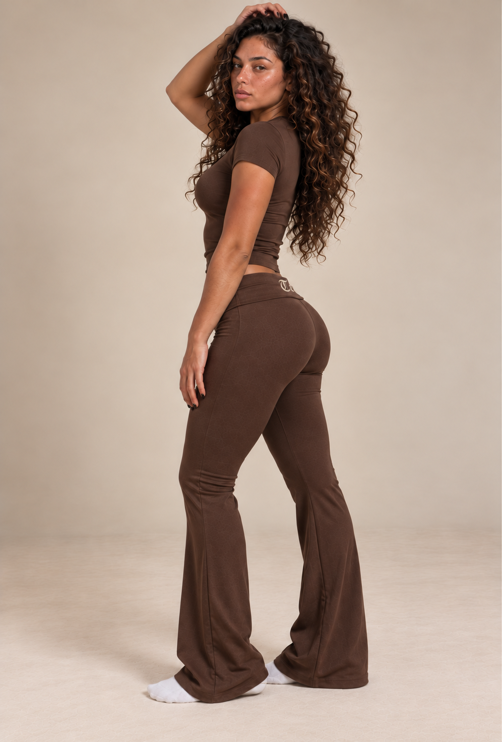 Side profile of a model wearing the Mocha Brown Lounge Set, with only the beginning of the centered rear waistband logo visible around the fold-over waist.